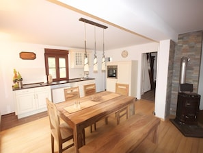 A kitchen with wooden cabinets, a dining table, pendant lights, and a stone fireplace. - Holiday Home 'Paula' with Mountain View, Wi-Fi and Air Conditioning (Forbach)
