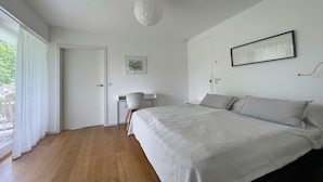 Un dormitorio con cama, escritorio, silla y lámpara colgante.