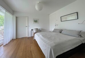 Un dormitorio con cama, escritorio, silla y lámpara colgante.