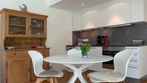 Una cocina moderna con armarios blancos, una mesa redonda y dos sillas blancas.