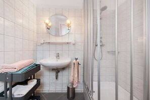Une salle de bain équipée d’un lavabo, d’un miroir, d’un porte-serviettes et d’une douche.