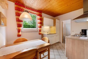 Une cuisine de taille réduite avec un coin repas, un plafond en bois et une fenêtre avec des rideaux.