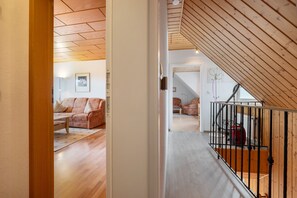 Un escalier en bois mène à une chambre située en mezzanine, qui offre une vue sur le salon.