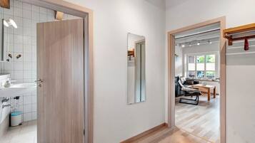 A modern interior with a wooden door, a mirror, a sink, and a dining area with a chair and table.