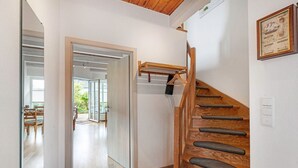 A staircase with wooden steps and grey carpet runners, a wooden handrail, and a wall-mounted coat rack. - Holiday Home Little Lighthouse-Backbord Terrace, Garden, Wi-Fi, Bike Garage, EV Charging (Fehmarn)