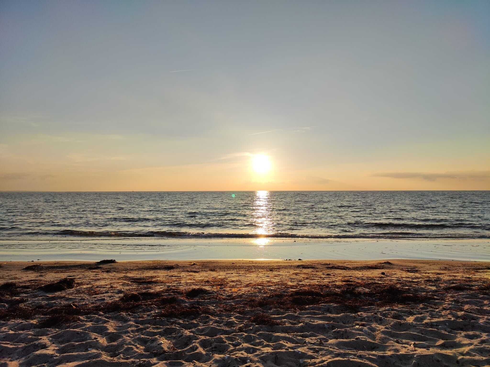 Una spiaggia con il sole che tramonta sull'oceano.