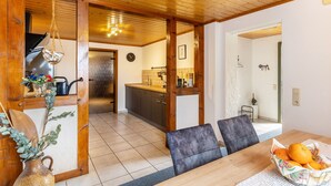 Een houten interieur met een eettafel, stoelen, een keuken en een gang naar een andere kamer.