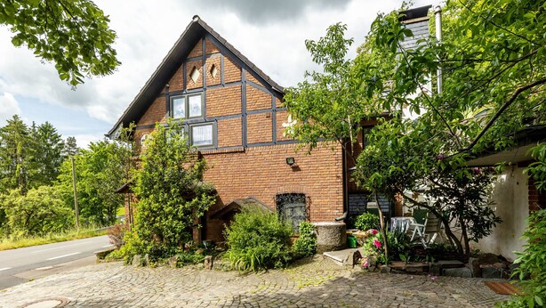 Een klassiek, bakstenen huis met een puntgevel, een voortuin en een geplaveid oprit.