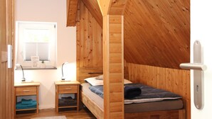 A small, wooden-paneled room with a bunk bed, a desk with a lamp, and a window with blinds. - Apartment 'Blum' with Private Terrace, Garden, and Wi-Fi (Schmallenberg)