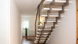 A modern staircase with a unique design, a wooden floor, and a potted plant in the background. - Apartment 'Blum' with Private Terrace, Garden, and Wi-Fi (Schmallenberg)