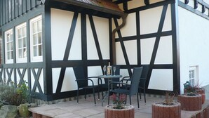 A patio with outdoor seating, a table with a bottle and glass, and potted plants. - Klaus and Erika Köninger: 'Erika' Apartment with Private Terrace and Wi-Fi (Sasbachwalden)