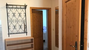 A hallway with wooden doors, a metal decorative panel, and a wooden bench. - Klaus and Erika Köninger: 'Erika' Apartment with Private Terrace and Wi-Fi (Sasbachwalden)