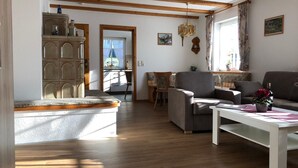 A living room with wooden beams, a sofa, a chair, a table, and a cabinet. - Klaus and Erika Köninger: 'Erika' Apartment with Private Terrace and Wi-Fi (Sasbachwalden)