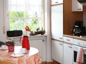 A kitchen with a window, a radiator, a coffee maker, and a table with a red kettle.