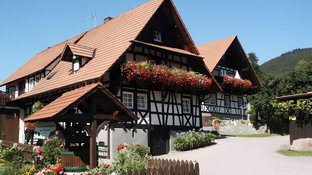 A traditional half-timbered building with a sloped roof, flower boxes, and a sign indicating it is a guesthouse. - Klaus and Erika Köninger: Apartment 'Klaus' with Shared Garden and Wi-Fi (Sasbachwalden)