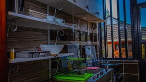 Una cucina con mobili in legno, un espositore per piatti verde e una finestra con vista sugli alberi.
