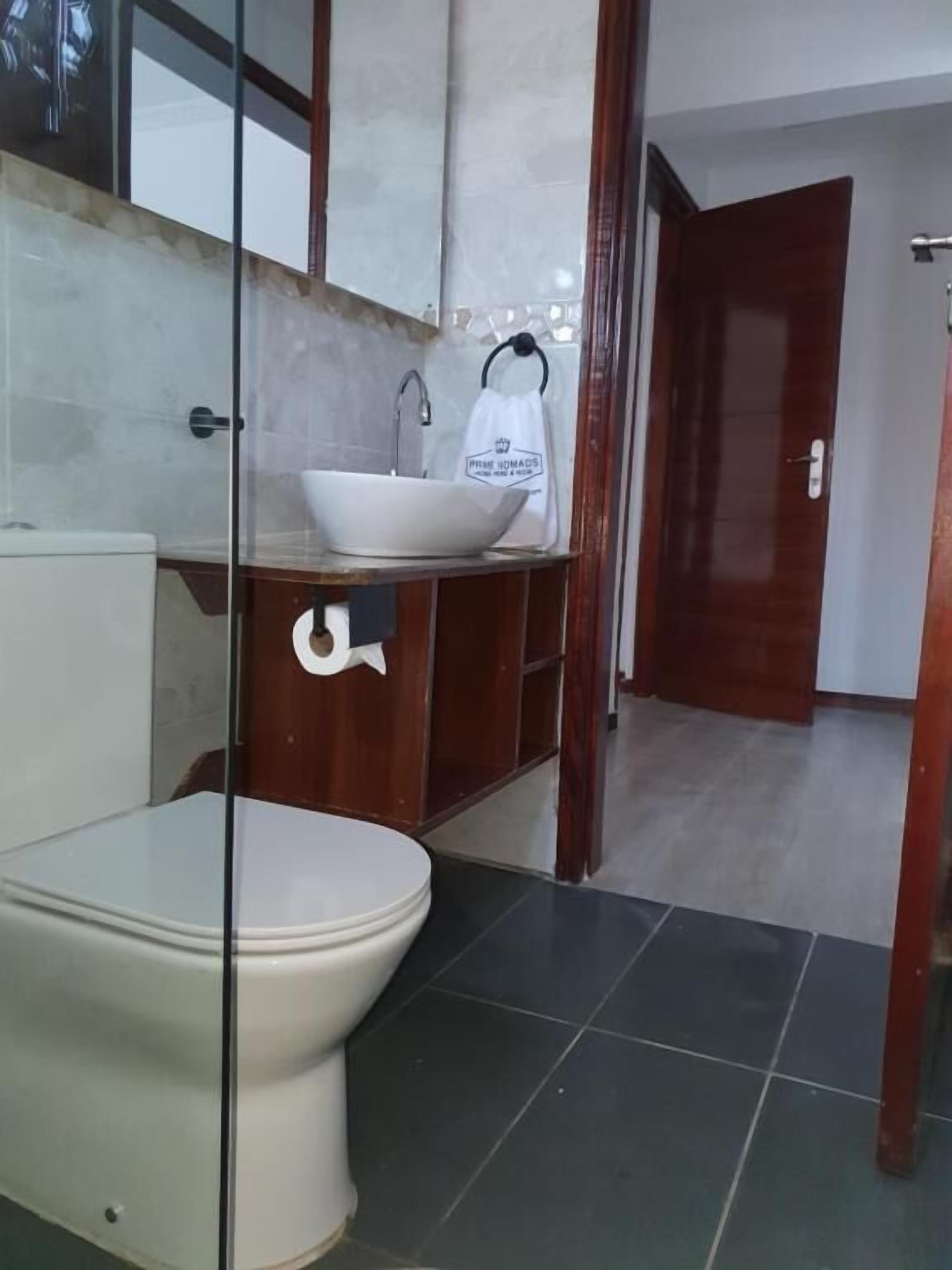 Un baño con inodoro y lavamanos blancos, y un mueble de madera debajo.