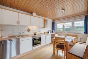 Une cuisine moderne avec des meubles en bois, un lave-vaisselle, un four et un coin repas comprenant une table et des chaises.