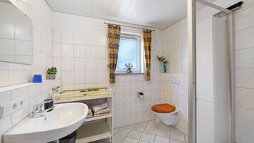 Une salle de bain équipée d’un lavabo, de toilettes, d’une douche et d’une fenêtre avec des rideaux.