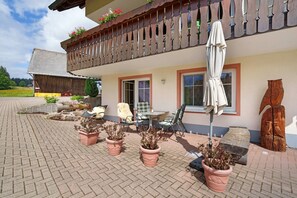 A building with a balcony, potted plants, outdoor furniture, and a wooden sculpture. - Apartment 'Schwalbennest' with Private Terrace, Shared Garden and Wi-Fi (St Peter)
