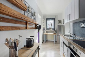A modern kitchen with wooden shelves, a toaster, a sink, and a refrigerator. - Apartment 'Riekes' with Mountain View, Private Terrace and Wi-Fi (Schmallenberg)