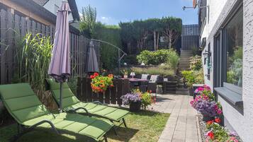 A patio area with green lounge chairs, a wooden fence, and potted plants.