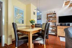 Un coin repas avec une table en bois et des chaises en cuir, une carte accrochée au mur, une bibliothèque et un téléviseur.