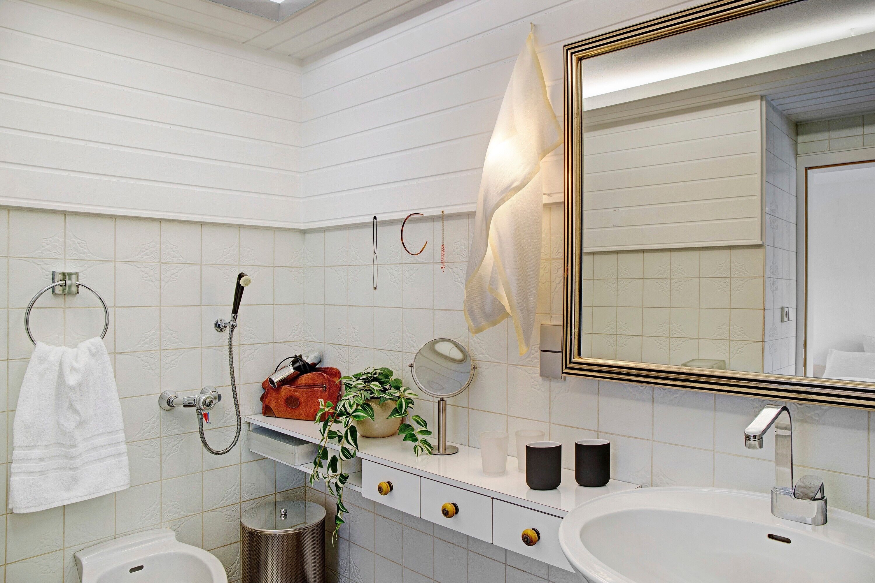 Une salle de bain avec un lavabo blanc, un miroir, un porte-serviettes et une douche.