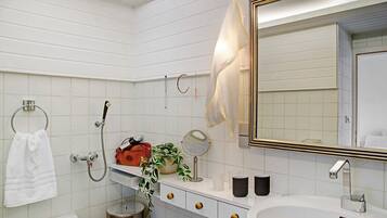Une salle de bain avec un lavabo blanc, un miroir, un porte-serviettes et une douche.
