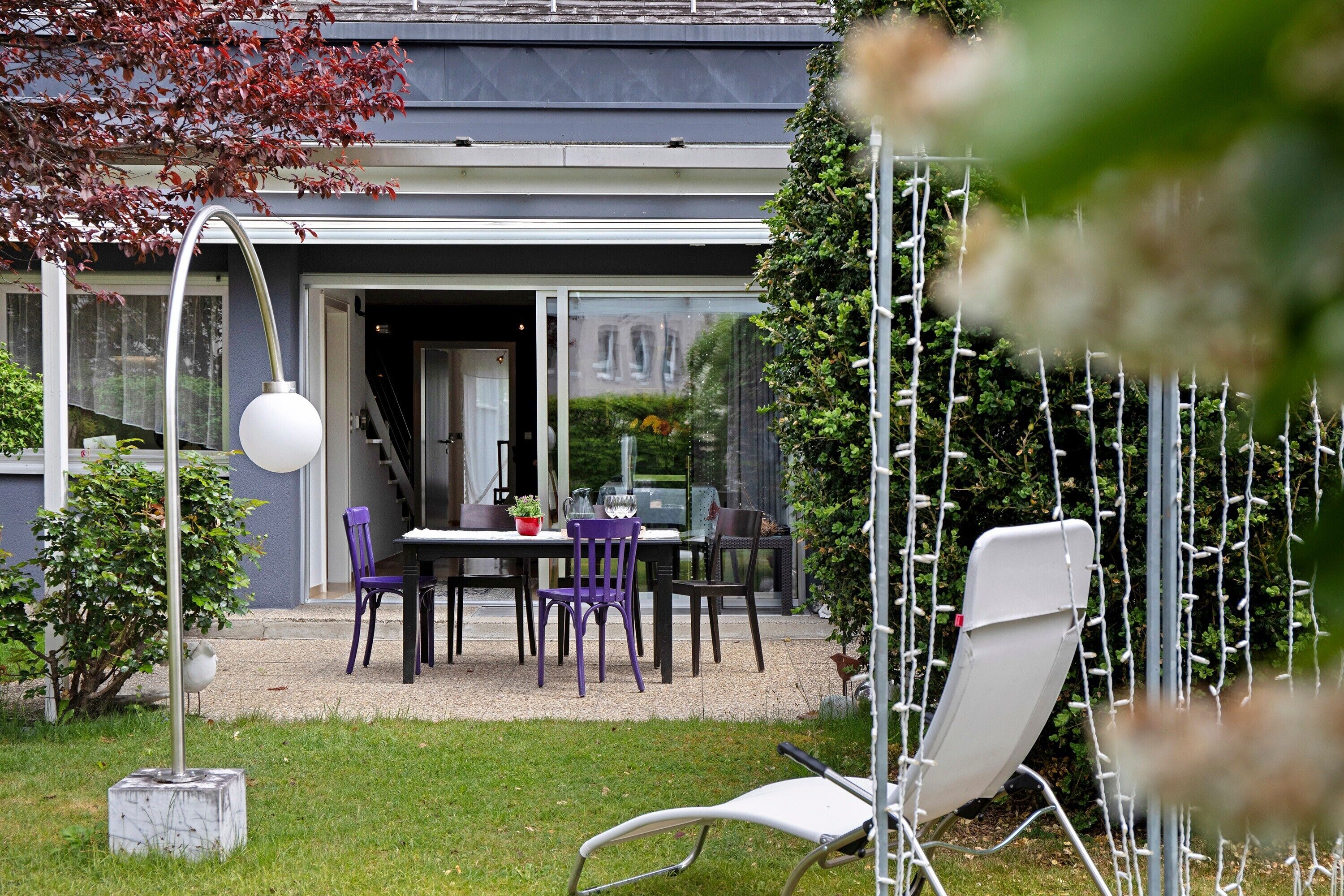 Een modern huis met een terras, tuinmeubilair en een tuin.