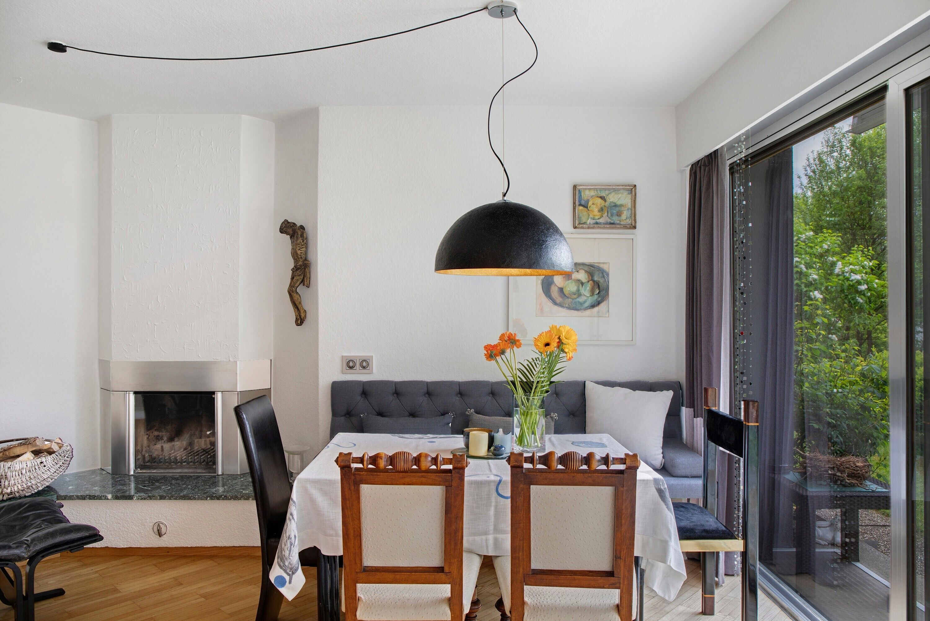 A dining area with a fireplace, a sofa, and a large window.
