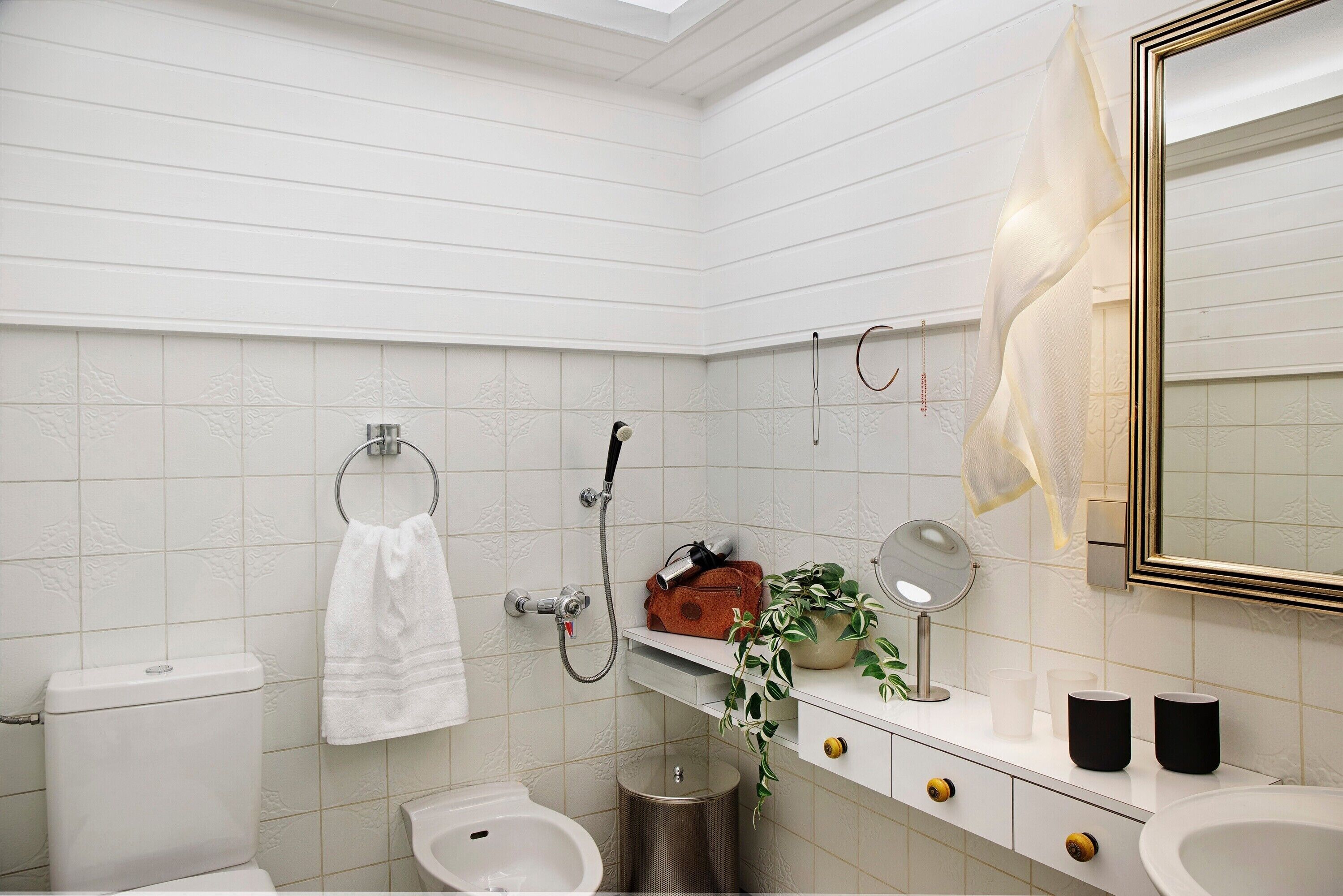 A bathroom with a toilet, bidet, sink, mirror, towel rack, and a hanging towel.
