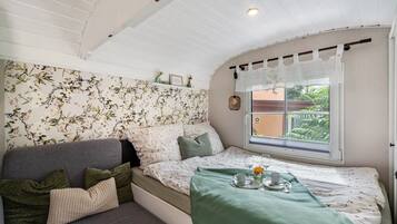 Una habitación acogedora con cama, sofá, ventana con vistas a vegetación y techo con vigas de madera.