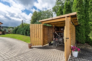 Une structure en bois dotée d’un toit, d’un support à vélos et d’une plante en pot.