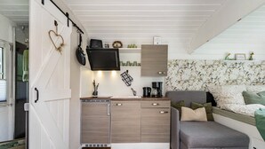 A compact kitchen with a dishwasher, a flat-screen TV, and a small countertop. - Tiny Home 'Amselnest' with Lake View, Private Terrace, and Wi-Fi (Oelsnitz/Vogtl.)