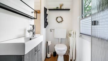 Un bany modern amb un vàter, un lavabo i un radiador blancs.