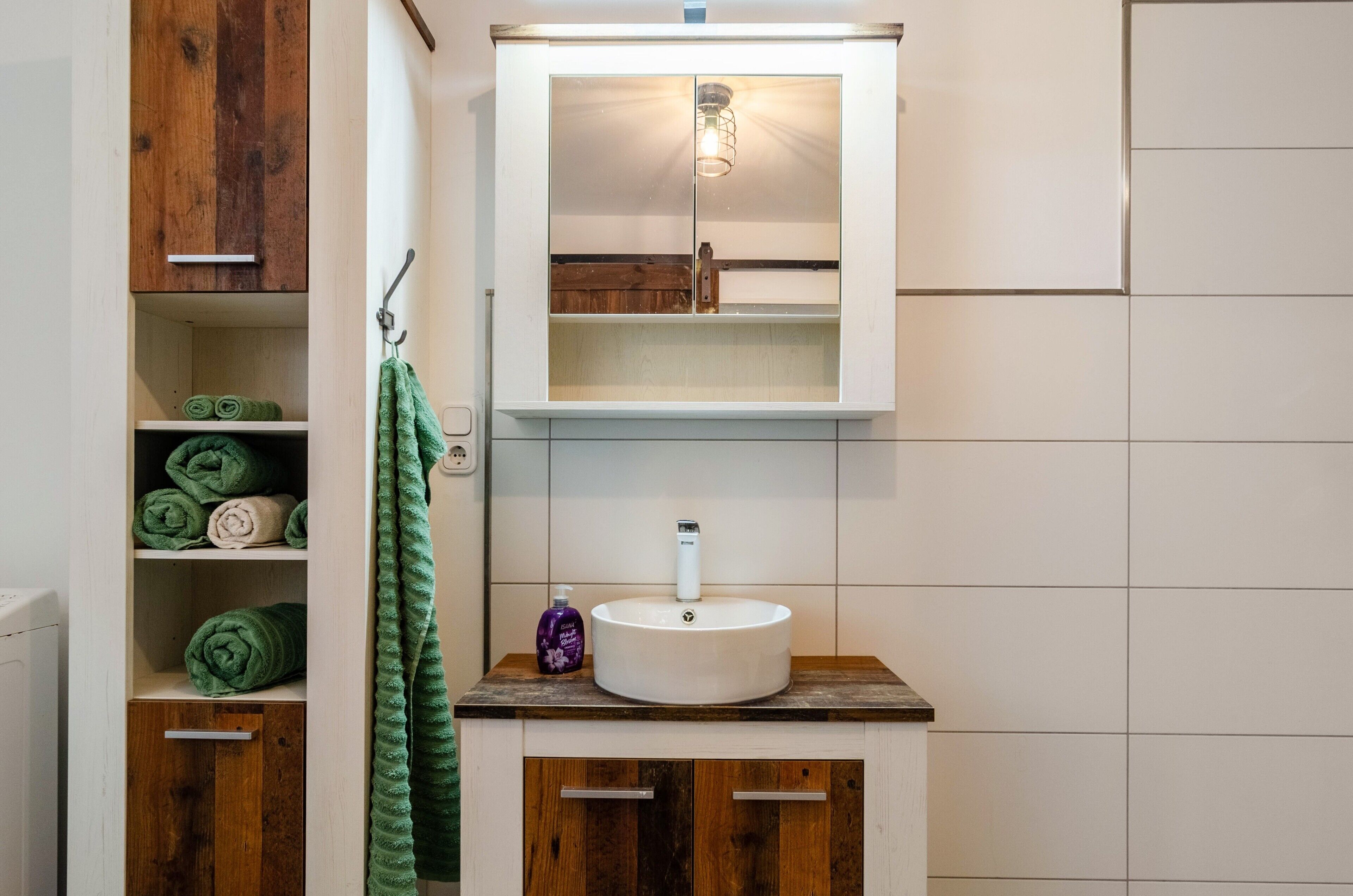 Une salle de bain avec un meuble-lavabo en bois, un lavabo blanc et un meuble à miroir.