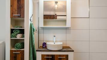 Une salle de bain avec un meuble-lavabo en bois, un lavabo blanc et un meuble à miroir.
