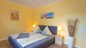 Une chambre à coucher avec un lit, des tables de chevet, des lampes et des œuvres d’art murales.
