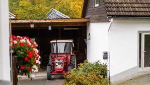 Ein roter Traktor vor einer Garage mit einem weißen Gebäude.