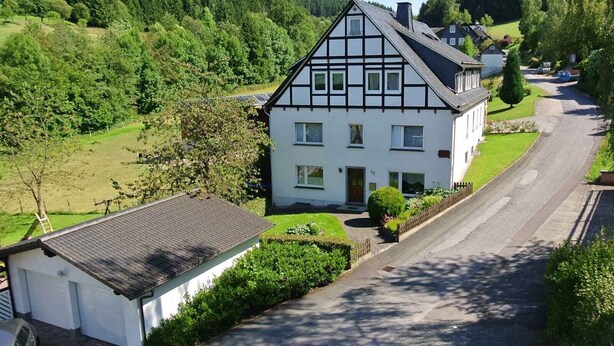 A two-story house with a sloped roof, a front porch, and a driveway leading to a street. - Apartment 'Kornkammer' with Shared Garden, Balcony and Wi-Fi (Schmallenberg)