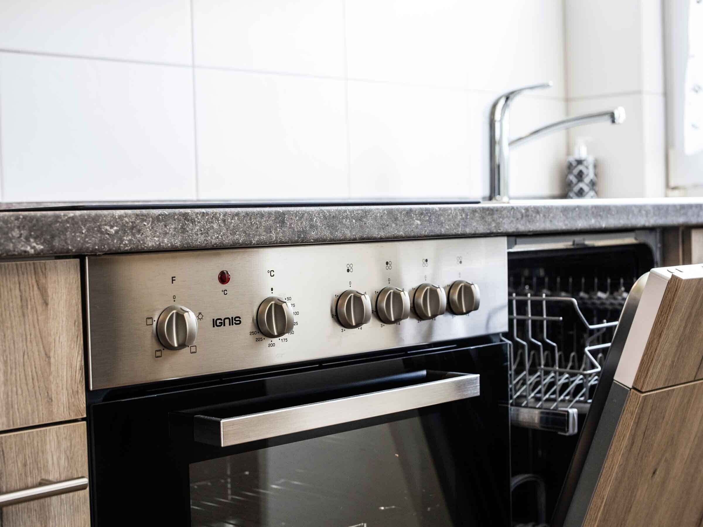 A kitchen with a stainless steel oven, wooden cabinets, and a dishwasher.