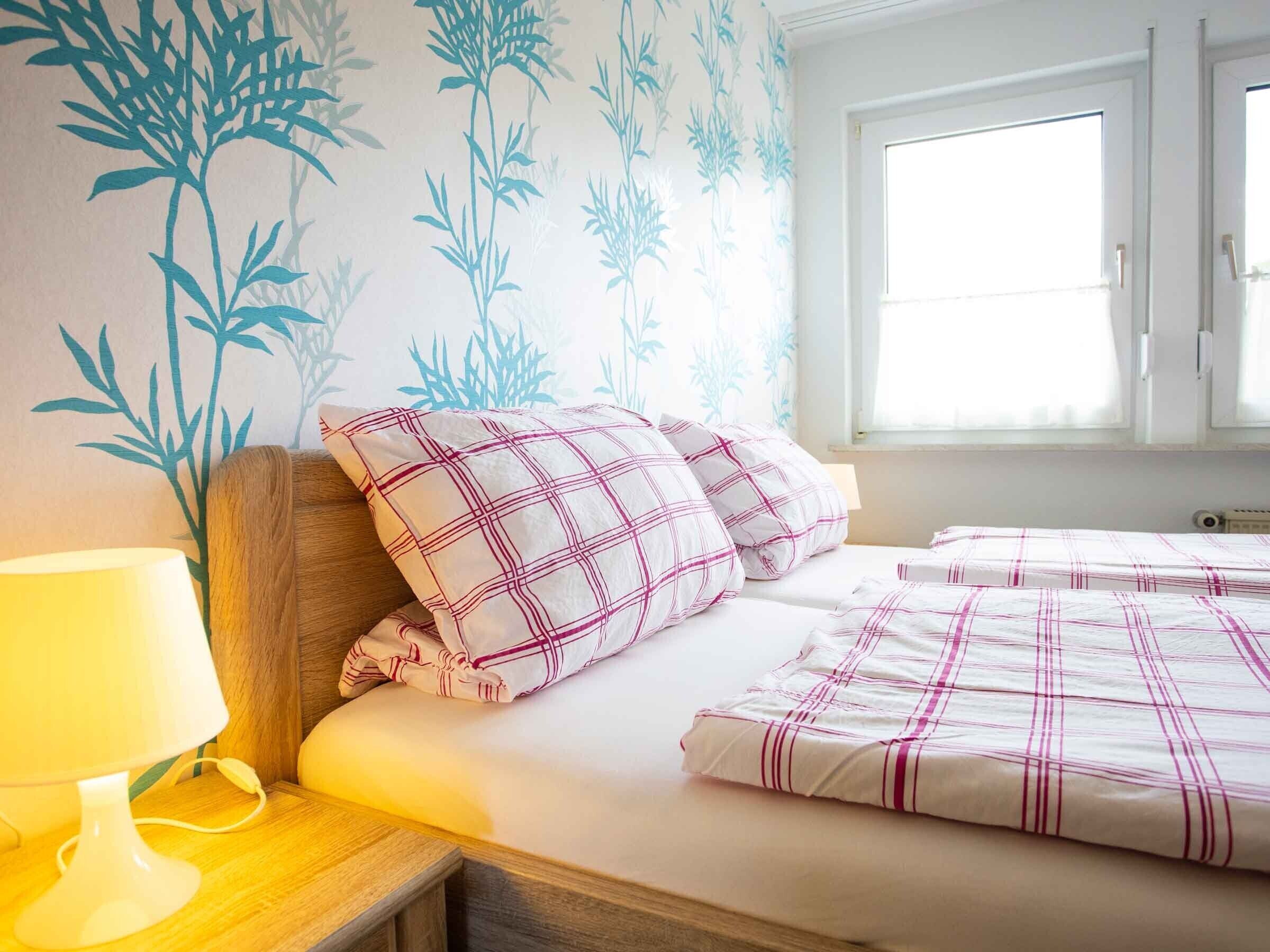 Ein Schlafzimmer mit einem Bett, Kissen, einer Nachttischlampe und einer Wand mit einem Bambus-Musterdesign.