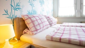 Ein Schlafzimmer mit einem Bett, Kissen, einer Nachttischlampe und einer Wand mit einem Bambus-Musterdesign.