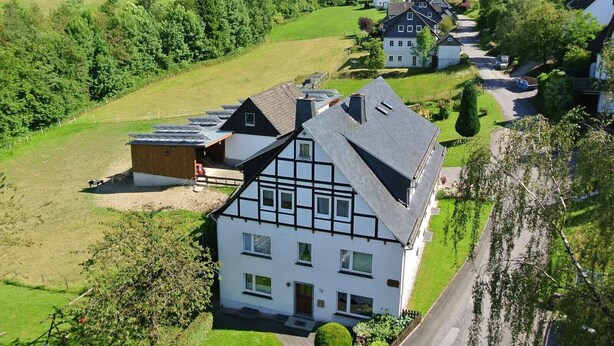 Ein ländliches Wohngebiet mit Häusern, einer Straße und umgebender Natur.