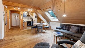 A spacious loft-style room with a dining area, kitchen, and seating area. - Apartment 'Schweizer' with Mountain View, Balcony and Wi-Fi (Bernau im Schwarzwald)