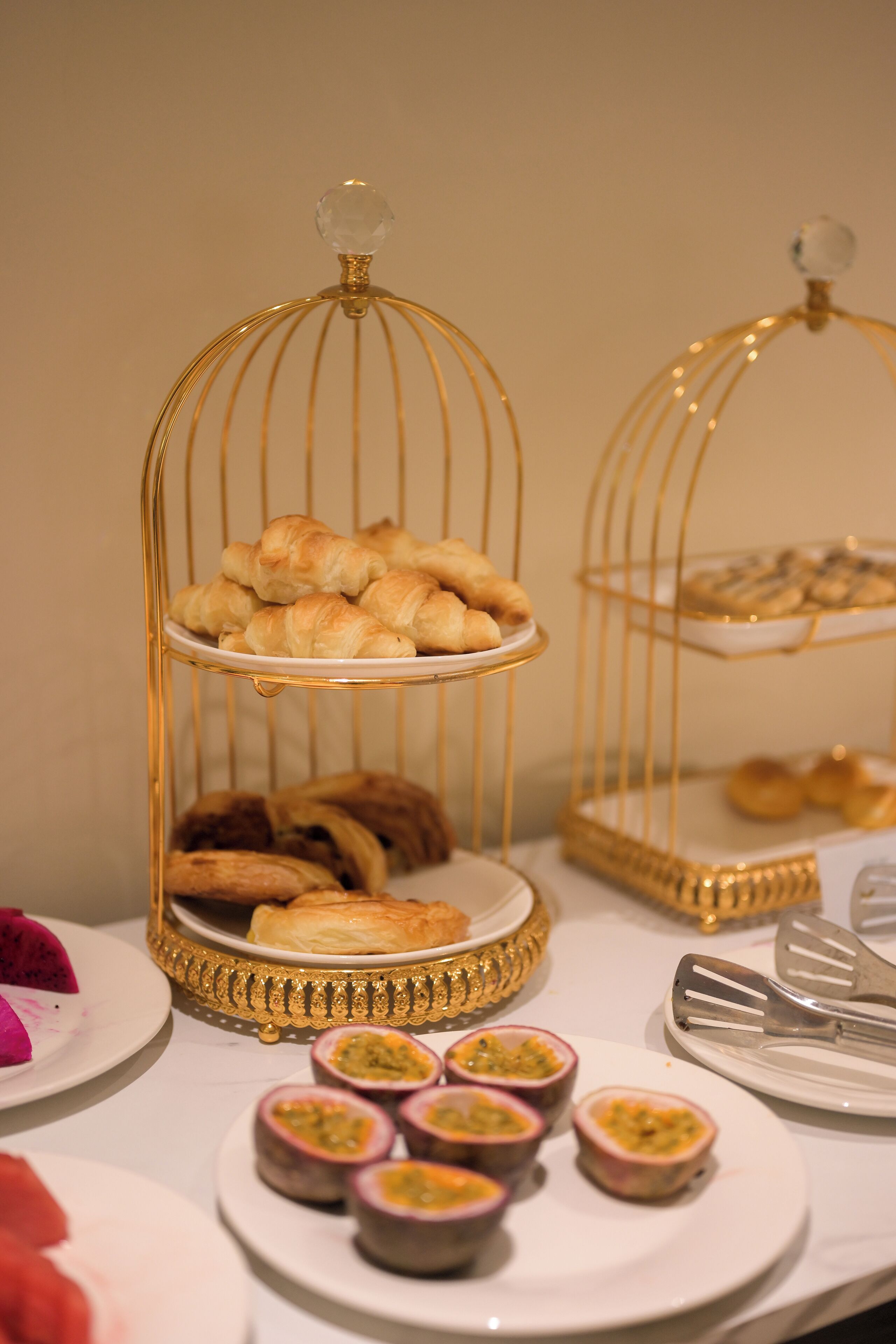 A buffet table with a variety of pastries and dishes, including croissants and passion fruit.