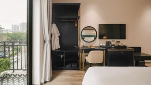 Een hotelkamer met een bed, een bureau, een stoel, een spiegel en uitzicht op de stad.