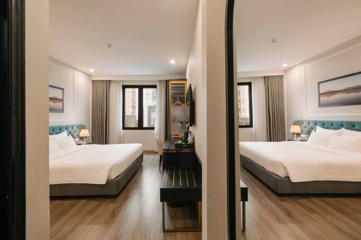 Una habitación de hotel con dos camas, un escritorio y un espejo.