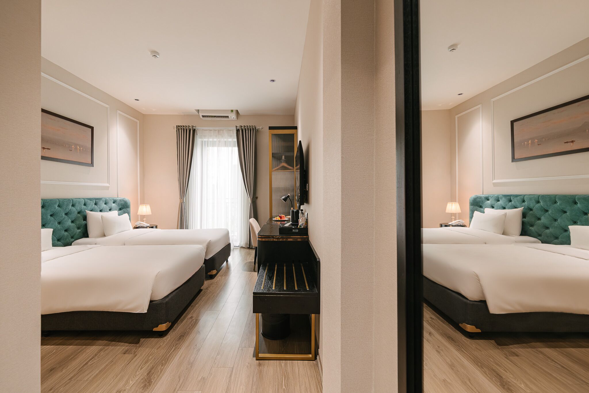 A hotel room with two beds, a desk, a television, and a window with curtains.